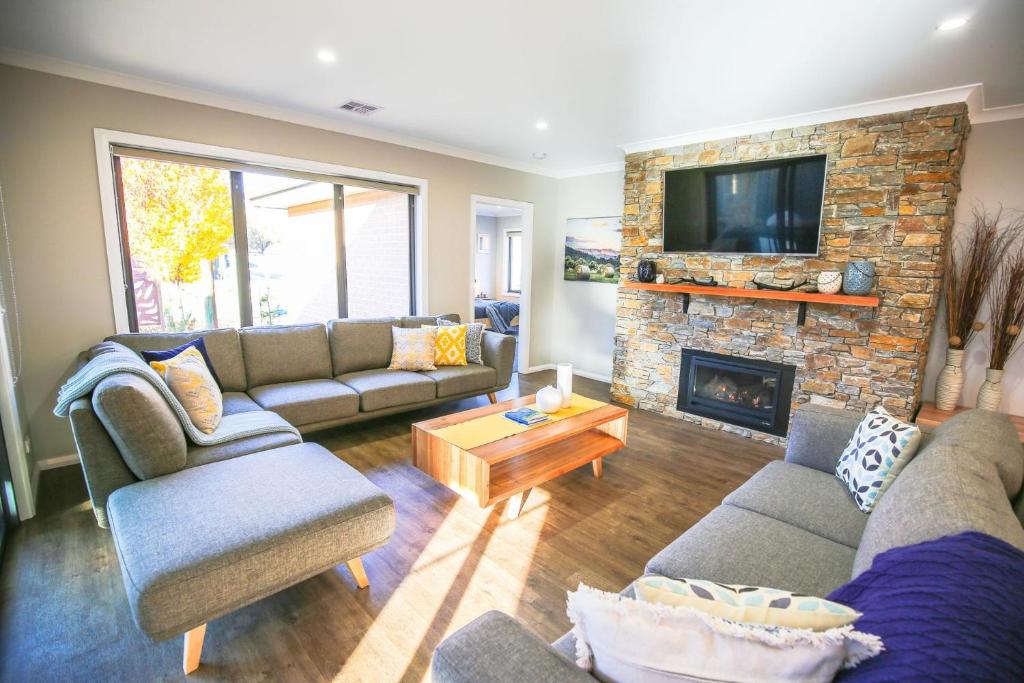 a living room with couches and a stone fireplace at Amaroo in Bright