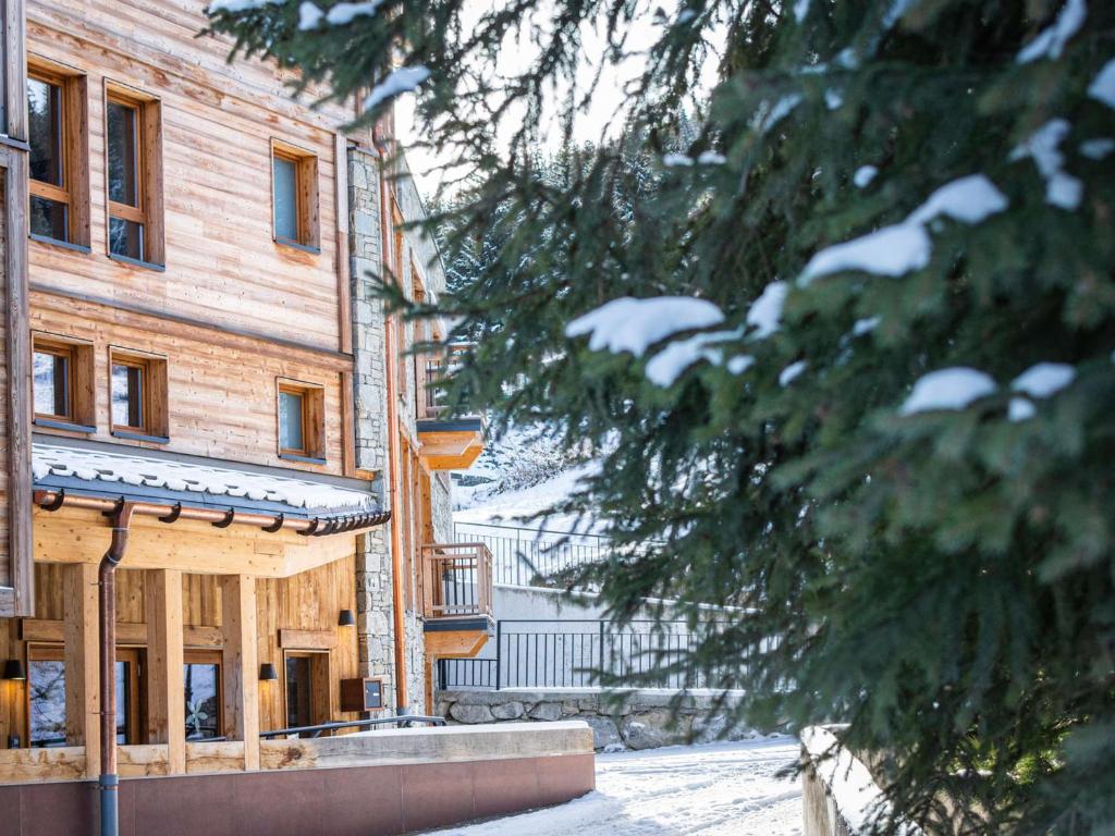 Appartement Courchevel 1650, 3 pièces, 8 personnes - FR-1-618-32 في كورشوفيل: مبنى خشبي فيه ثلج على فروع الشجر