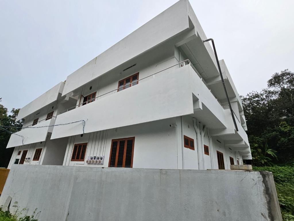 een wit gebouw met een muur ervoor bij ZEAL HOMES And Apartments Koothattukulam in Kuttāttukulam