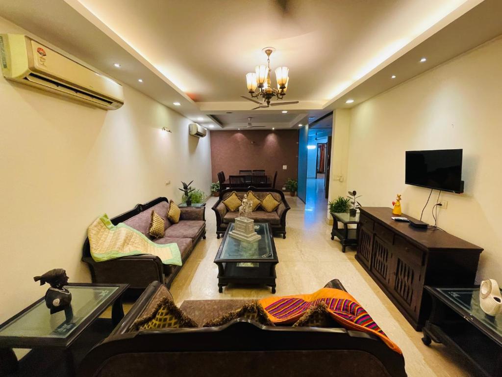 Il comprend un salon avec des canapés et une télévision à écran plat. dans l'établissement Fortune Home Service Apartment 4Bhk,J-191 Saket, à New Delhi