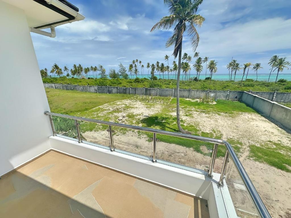 een balkon met uitzicht op het strand en de palmbomen bij Tropical Gem: 3-BR Beach Villa in Pingwe