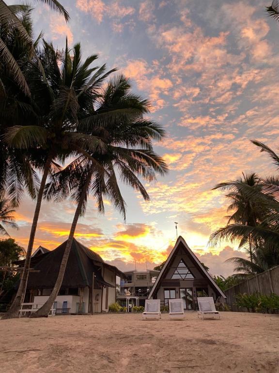 einen Strand mit zwei Palmen und einem Gebäude in der Unterkunft Surya Beach Resort Palawan in Aborlan