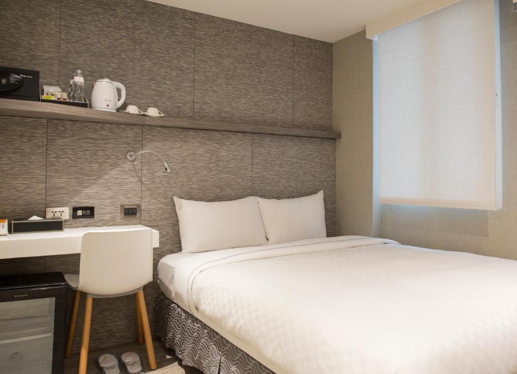 a bedroom with a bed and a desk and a white bed at Cityinn Hotel Taipei Station Branch I in Taipei