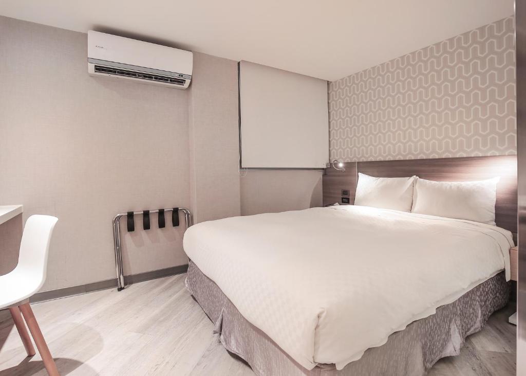 a bedroom with a large white bed and a chair at Cityinn Hotel Taipei Station Branch I in Taipei