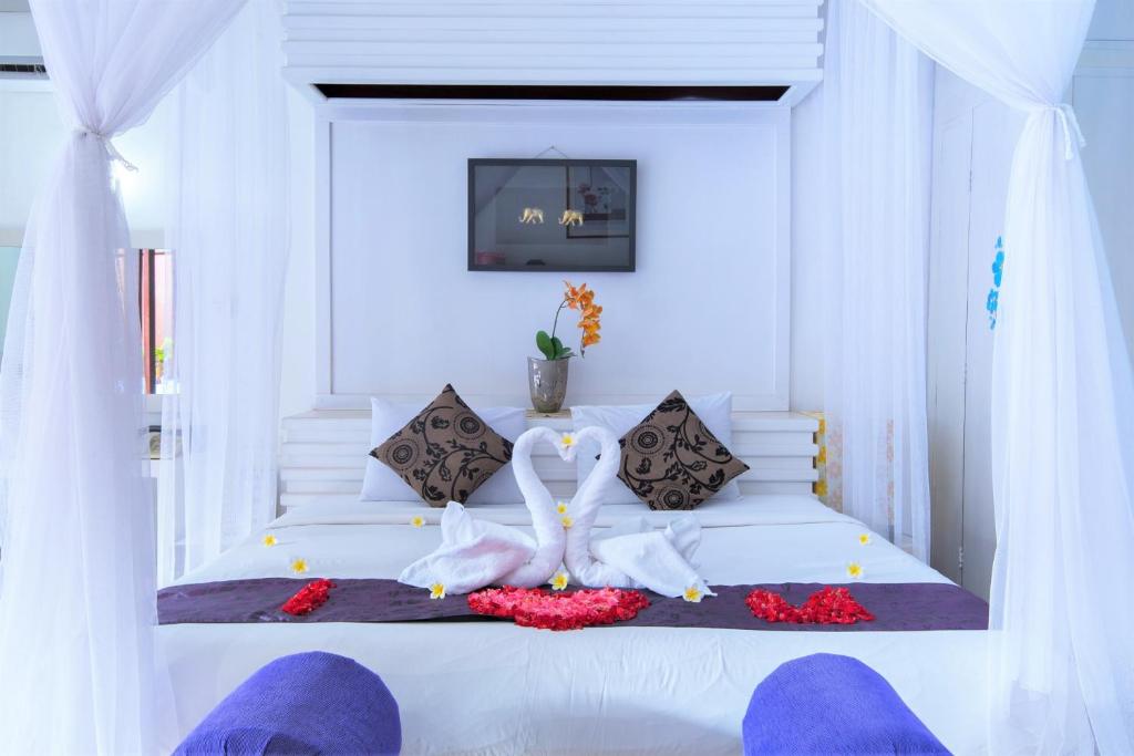One Bedroom Private Villa Kuta في سمينياك: غرفة نوم بسرير ابيض عليها بجعتين