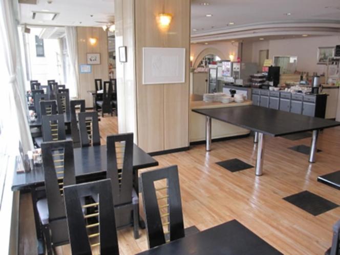 un ristorante con tavoli e sedie neri in una stanza di Hotel Alpha-One Mishima a Mishima