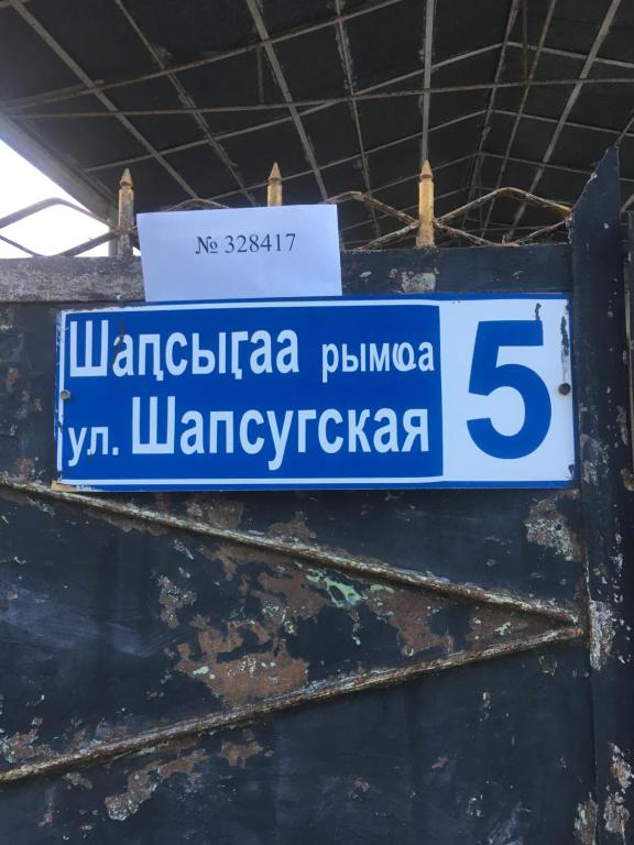 a blue and white street sign hanging from a wall at Частный дом in Sukhum