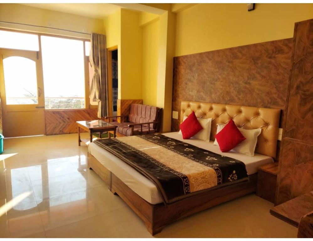 um quarto com uma cama grande e almofadas vermelhas em The Mountain Paradise Hotel, Rewalsar, H.P. em Mandi