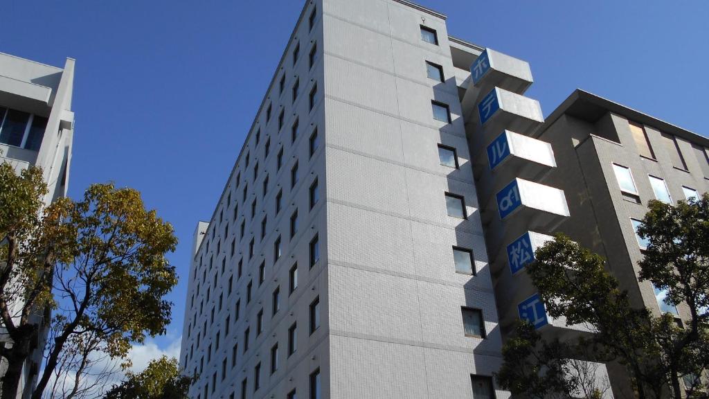 a tall white building with blue signs on it at Hotel Alpha-One Matsue in Matsue