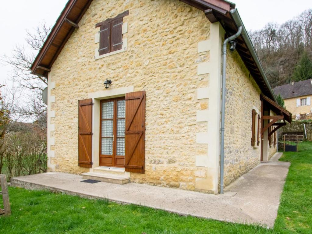 uma casa de pedra com uma porta de madeira e um quintal em Gîte Tursac, 4 pièces, 6 personnes - FR-1-616-151 em Tursac