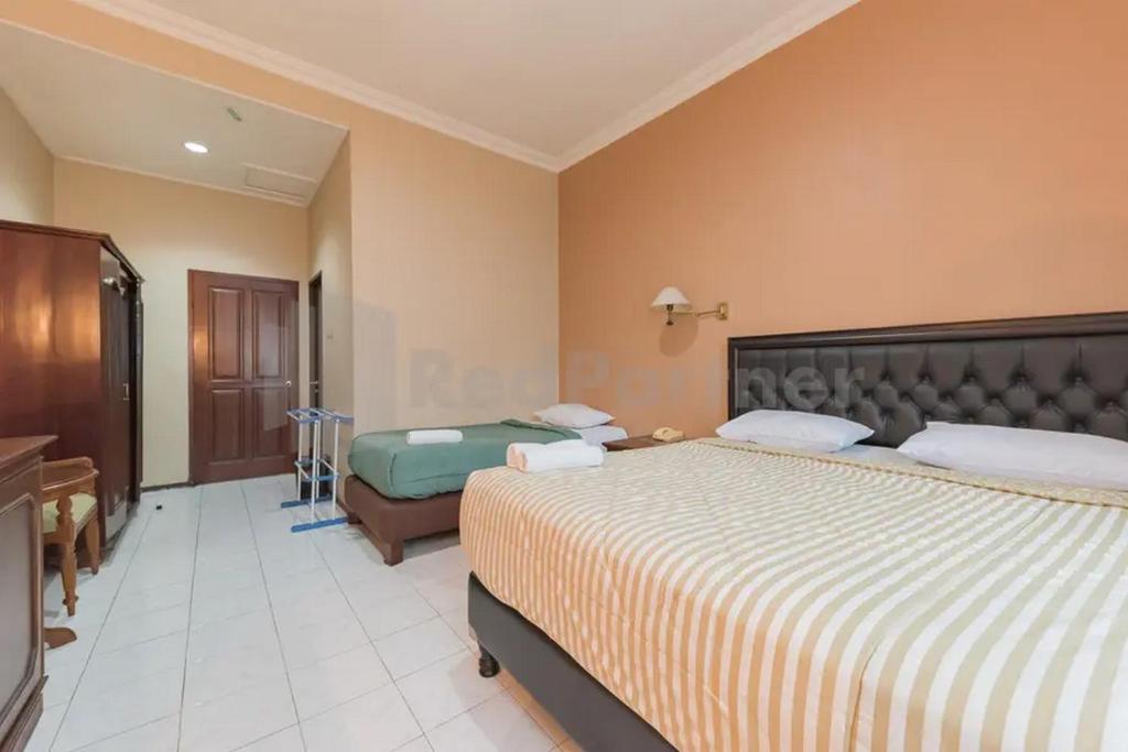 a hotel room with two beds and a desk at Hotel ayong Linggarjati Kuningan Mitra RedDoorz in Kuningan