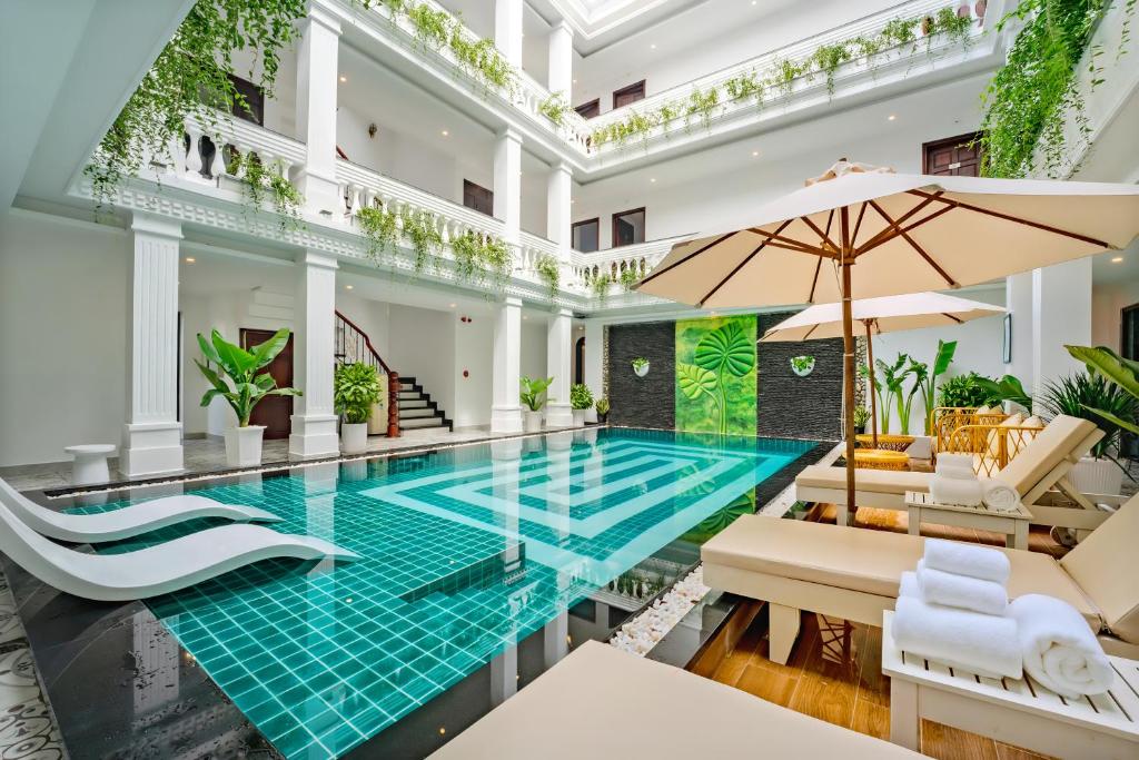 a pool in a building with chairs and an umbrella at Royal Mansion Boutique Hoi An in Hoi An