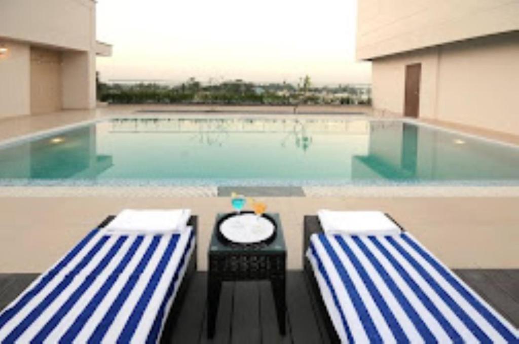 a swimming pool with two chairs and a table in front of it at Hotel Blue Saphire Countryside Haldwani in Haldwāni