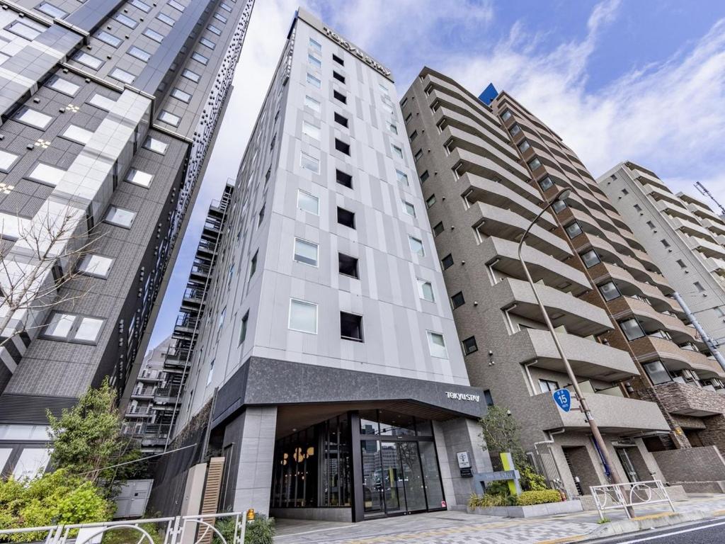 a tall white building with two tall buildings at Tokyu Stay Takanawa Shinagawa Area in Tokyo