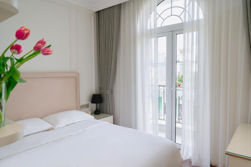 a bedroom with a white bed and a window with pink flowers at The Nguyens - Pink Church View in Ho Chi Minh City