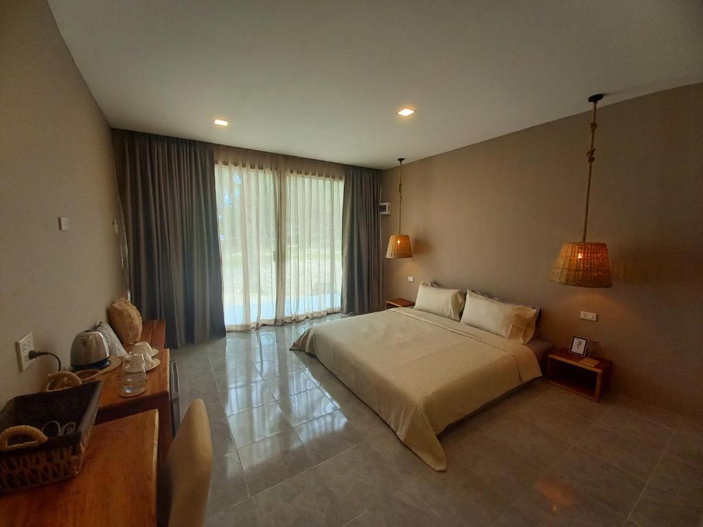 a bedroom with a large bed and a large window at Koh Kood Club in Ko Kood