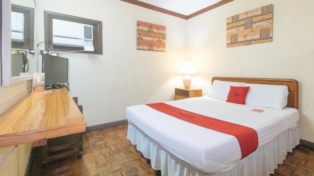 a hotel room with a bed and a desk at RedDoorz at Broadway Court Apartelle II Quezon City in Manila