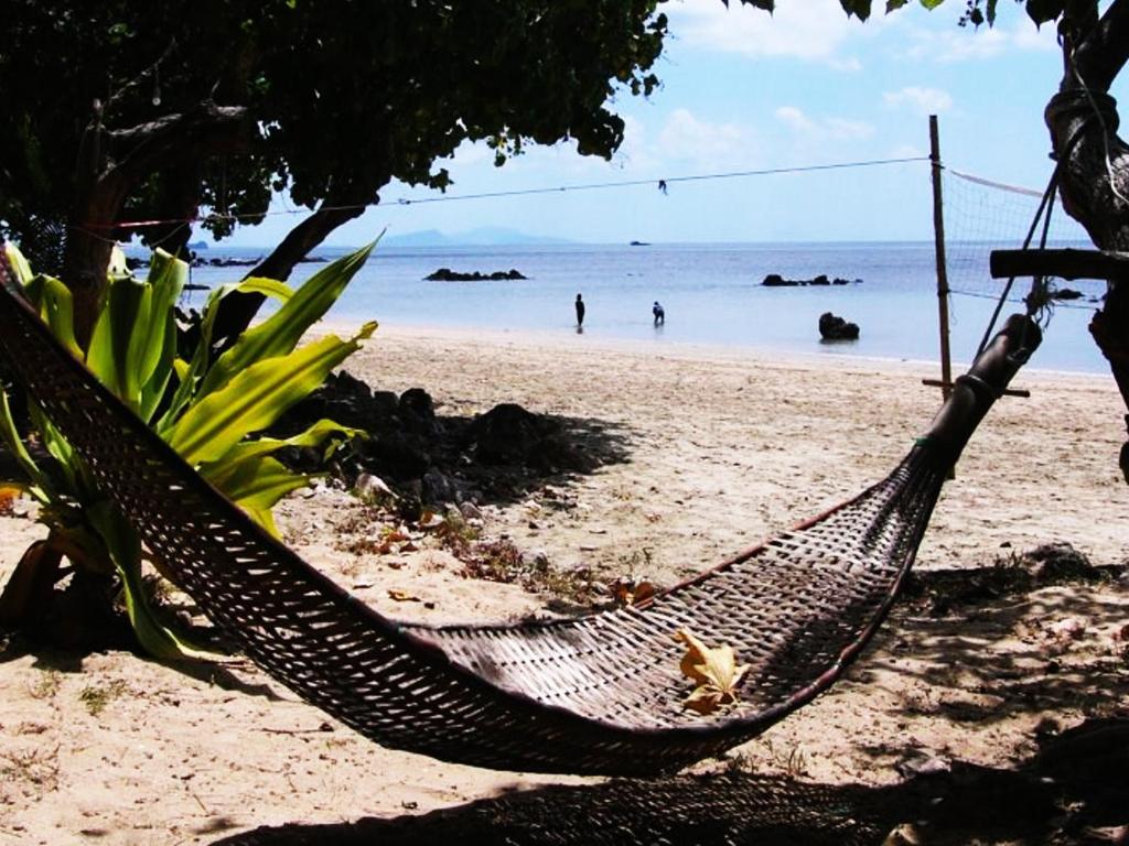 a hammock on a beach with people in the water at Room in Bungalow - Breathtaking Cottage of Koh Pu in Ko Jum