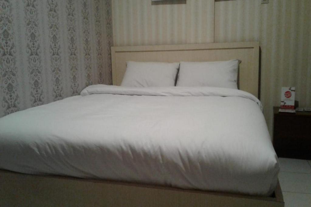 查亞普拉的住宿－OYO 93485 Hotel Kenzie Sentani，一张配有白色床单和枕头的大床