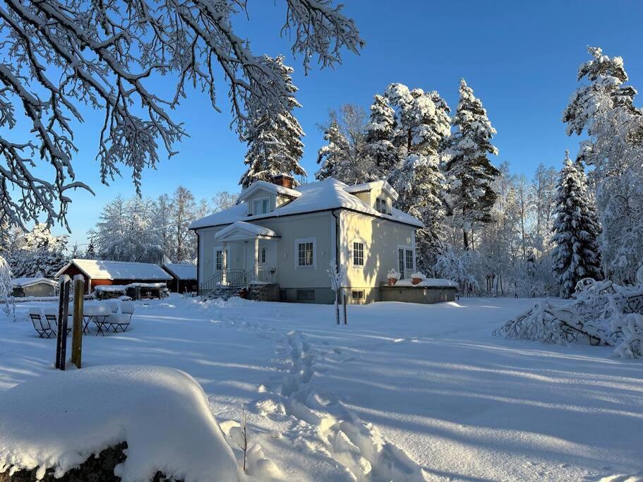 uma casa coberta de neve num quintal com árvores em Lugnet em Skebobruk