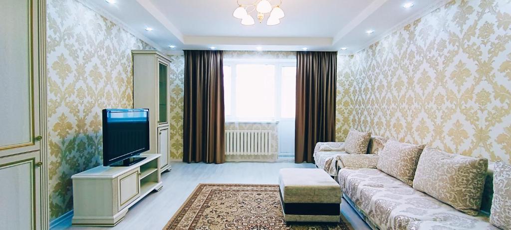 ein Wohnzimmer mit einem Sofa und einem TV in der Unterkunft Comfortable apartment on Sarayshyq street 7-1 in Astana