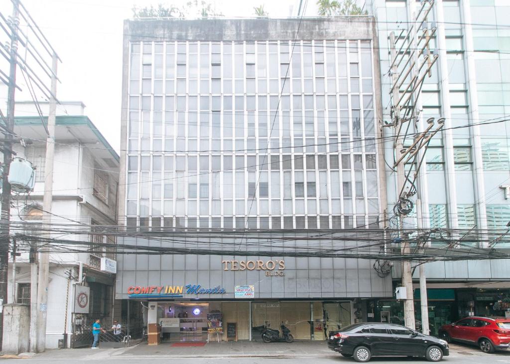 馬尼拉的住宿－RedDoorz at Comfy Inn Ermita Manila，一座白色的大建筑,前面有一辆汽车