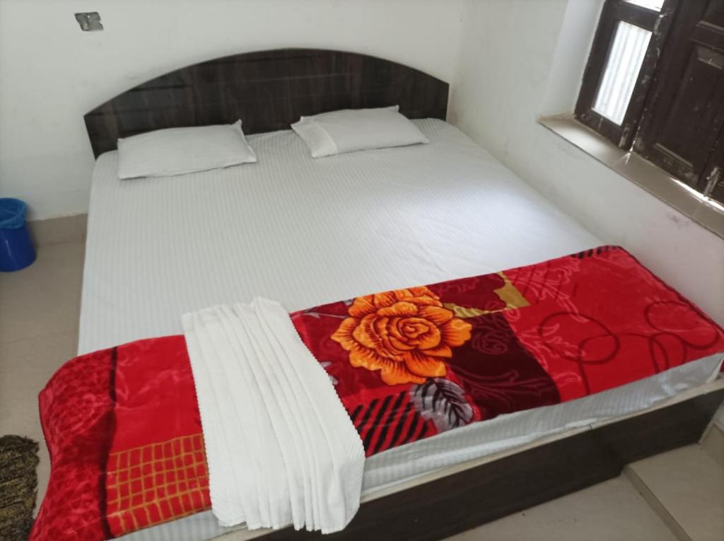 Una cama con una manta roja y blanca. en Hotel Dharam Mukti Utsav Bhawan (DMUB) en Raxaul