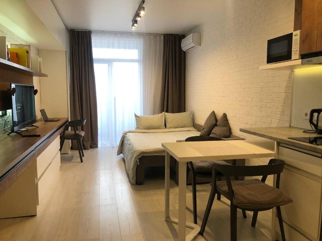 a room with a bed and a table and a kitchen at Сучасна, стильна студія біля ВДНГ in Kyiv