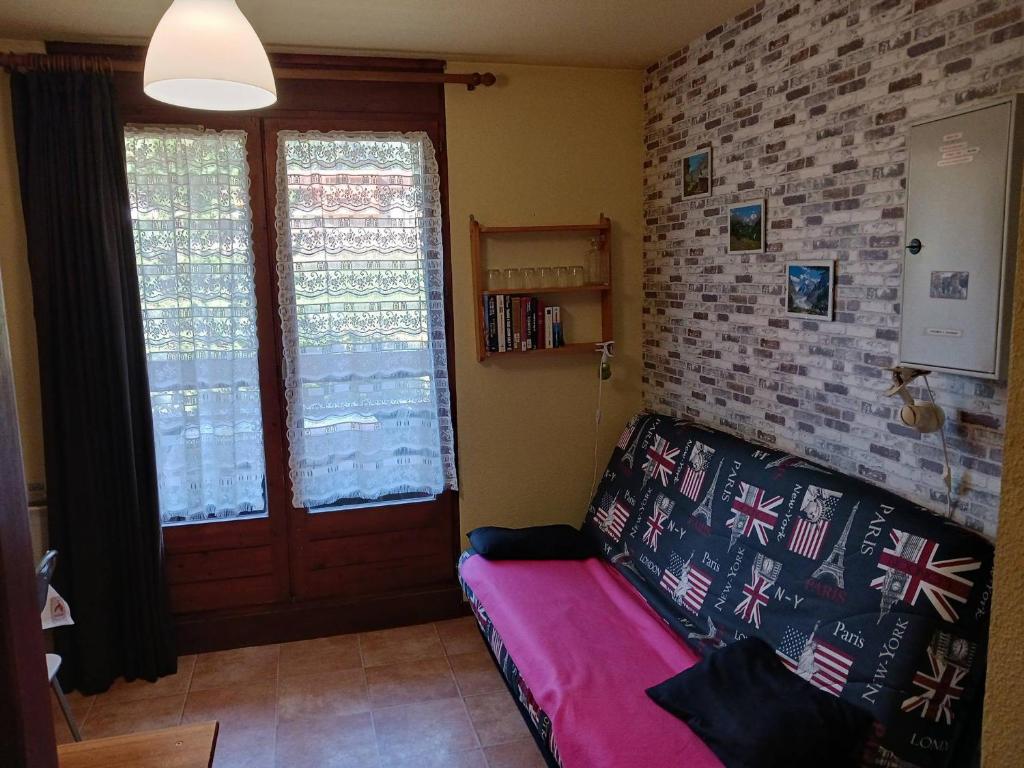 a living room with a couch and two windows at Studio Bourg-Saint-Maurice, 1 pièce, 3 personnes - FR-1-411-920 in Bourg-Saint-Maurice