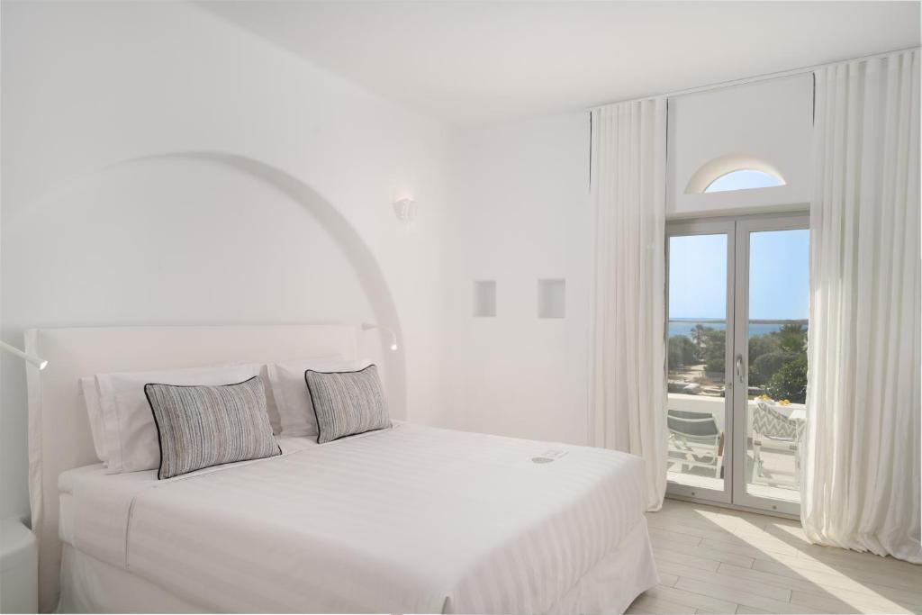 a white bedroom with a bed and a large window at White Dunes Luxury Boutique Hotel in Santa Maria