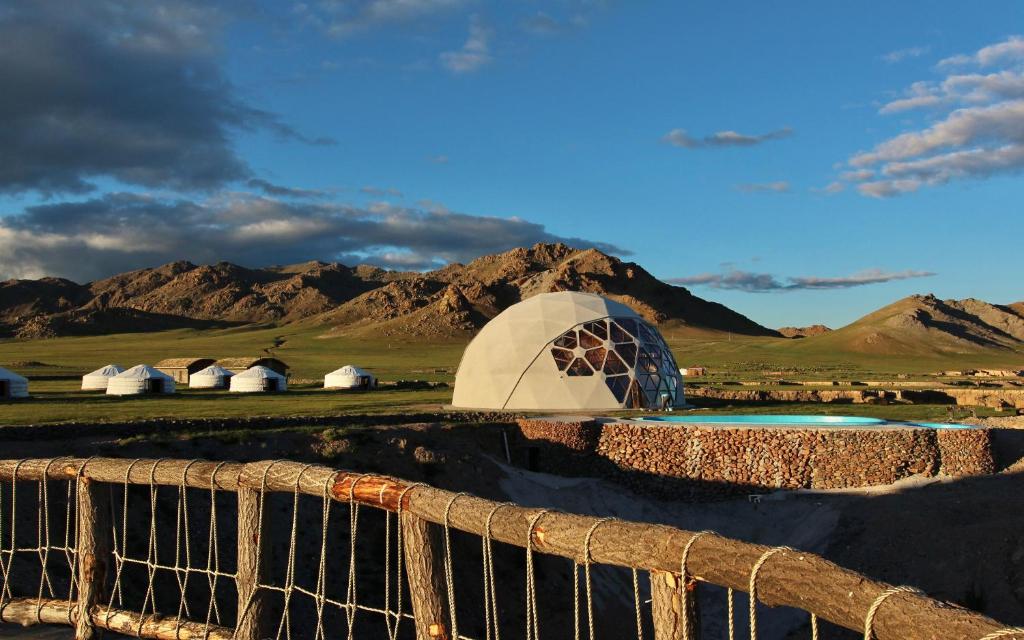 a tent in the middle of a field with mountains at ViaVia Harganat Lodge 