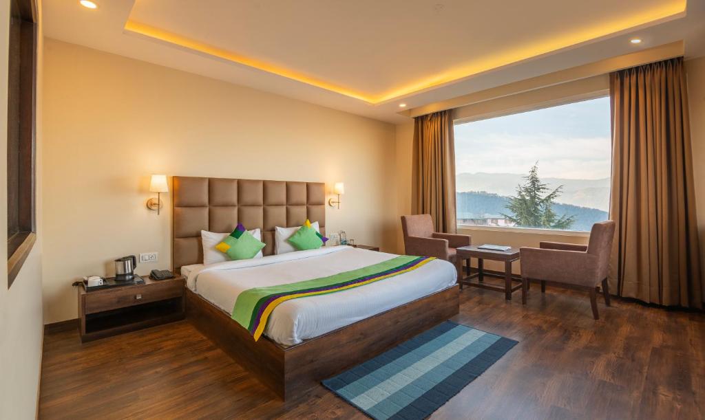 a hotel room with a bed and a large window at Treebo Trend The Northern Retreat Resort With Mountain View in Shimla