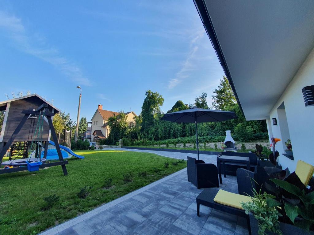 patio z huśtawką, parasolem i placem zabaw w obiekcie AThome w mieście Czchów
