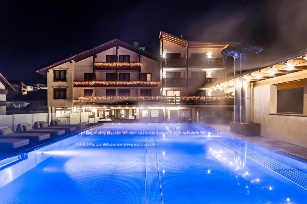 uma piscina à noite com um hotel ao fundo em Hotel Ariston Garden & Spa em Monclassico