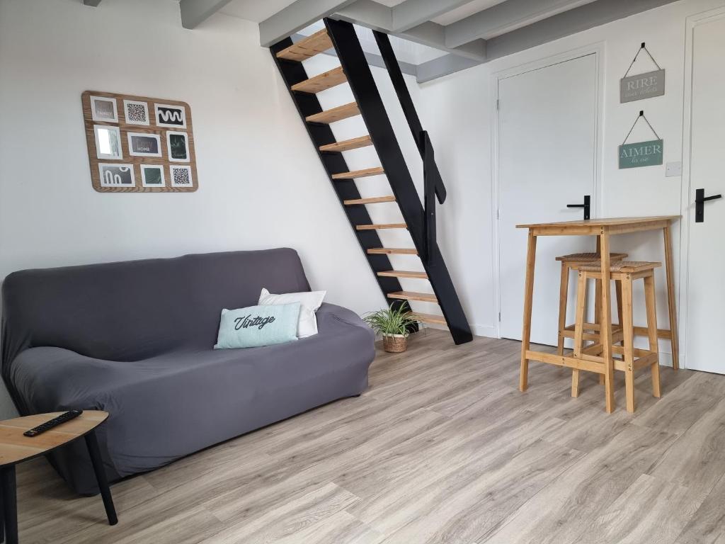 Una sala de estar con un sofá y una escalera. en Studio cocooning au calme, proche centre-ville et centre commercial, en Challans