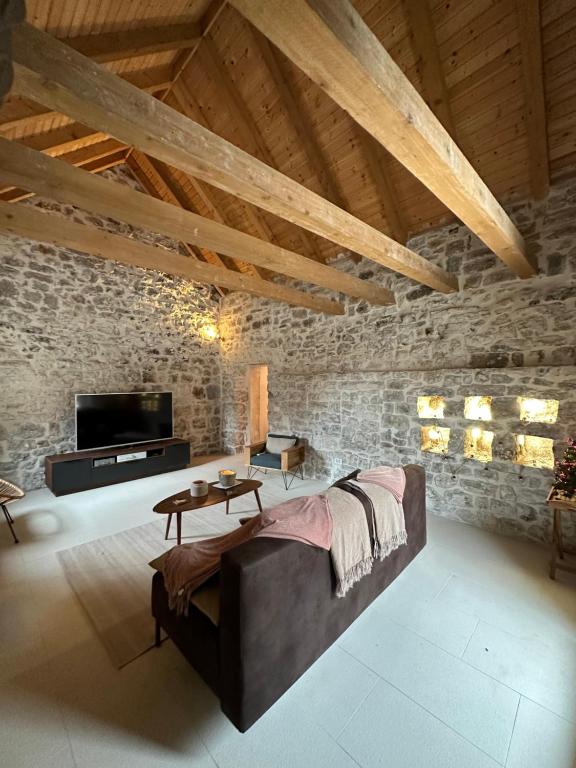a living room with a couch and a tv at Maison Laurel - Exquisitely Renovated Centuries Old Stone Estate With Private Pool, Near Split and Omiš in Gata