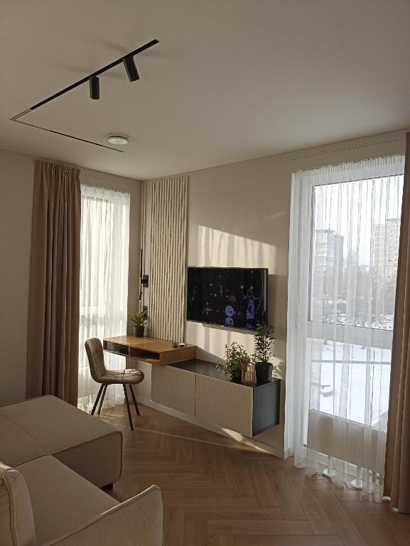 a living room with a television and a table and chairs at Apartments with a balcony and an impressive terrace on the roof of the house - PRIVATE FREE CAR PARKING in Vilnius