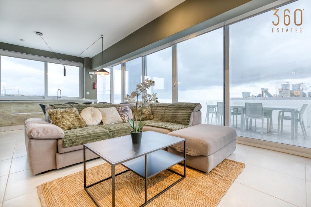 ein Wohnzimmer mit einem Sofa und einem Tisch in der Unterkunft LUX Duplex Penthouse w/ Expansive Rooftop Terrace by 360 Estates in San Ġwann
