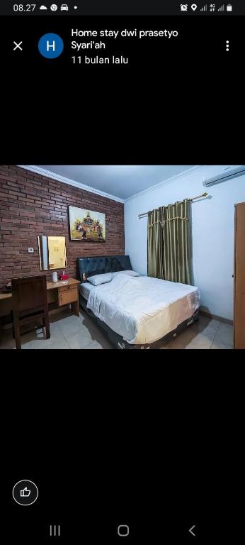 a bedroom with a bed and a desk and a brick wall at Homestay dwi prasetyo in Kembanglimus