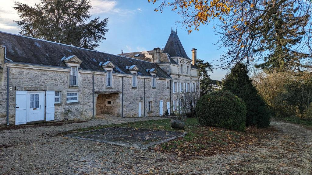 una antigua casa de piedra con un gran edificio en Château de Saugé, en Saivres