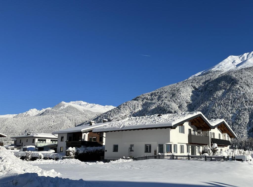 a building in the snow with mountains in the background at Apart Aria in Längenfeld