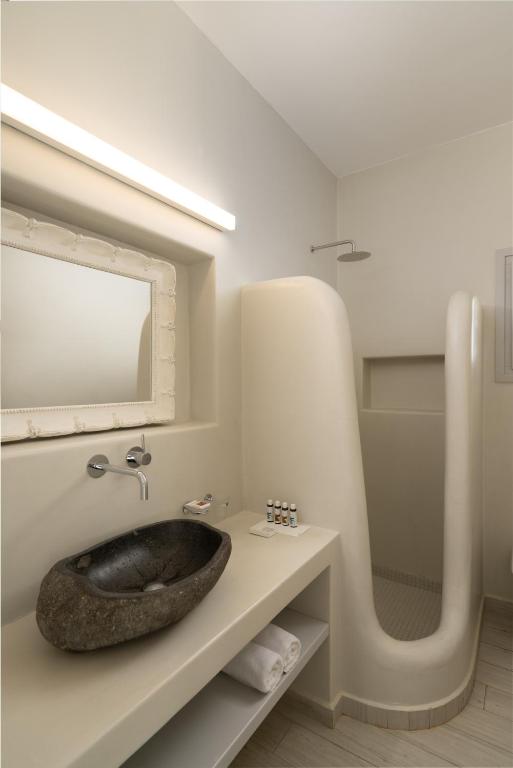 a bathroom with a stone sink on a counter at White Dunes Luxury Boutique Hotel in Santa Maria