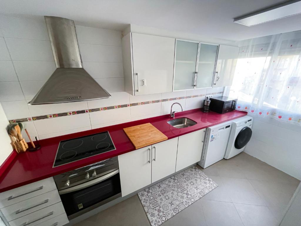 a kitchen with white cabinets and a red counter top at Habitaciones privadas con baño en piso céntrico Gandía in Gandía