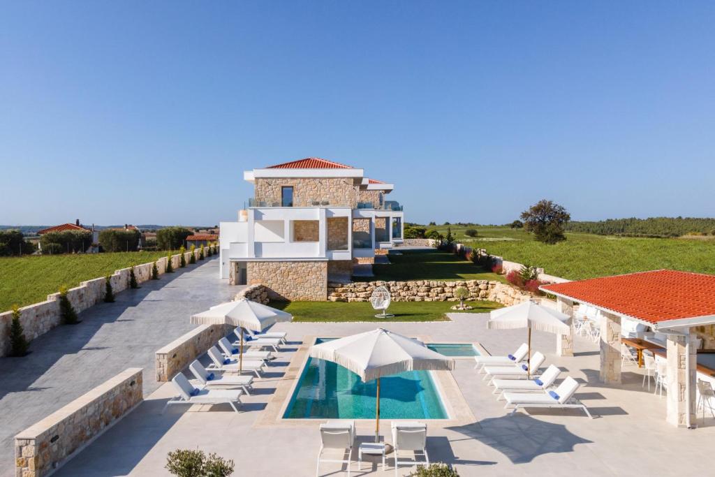 un complexe avec une piscine, des chaises et un bâtiment dans l'établissement Anna Mare Luxury Apartments, à Afytos