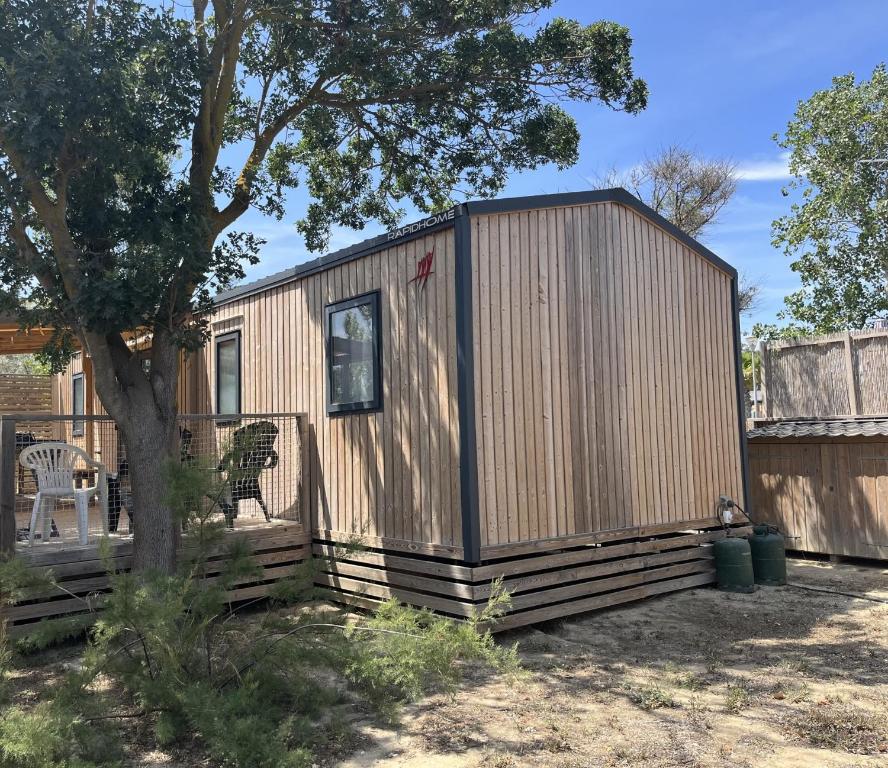 une petite maison en bois dans une cour avec un arbre dans l'établissement LES DUNES - TORREILLES - Chez Cassandre et Nico, à Torreilles