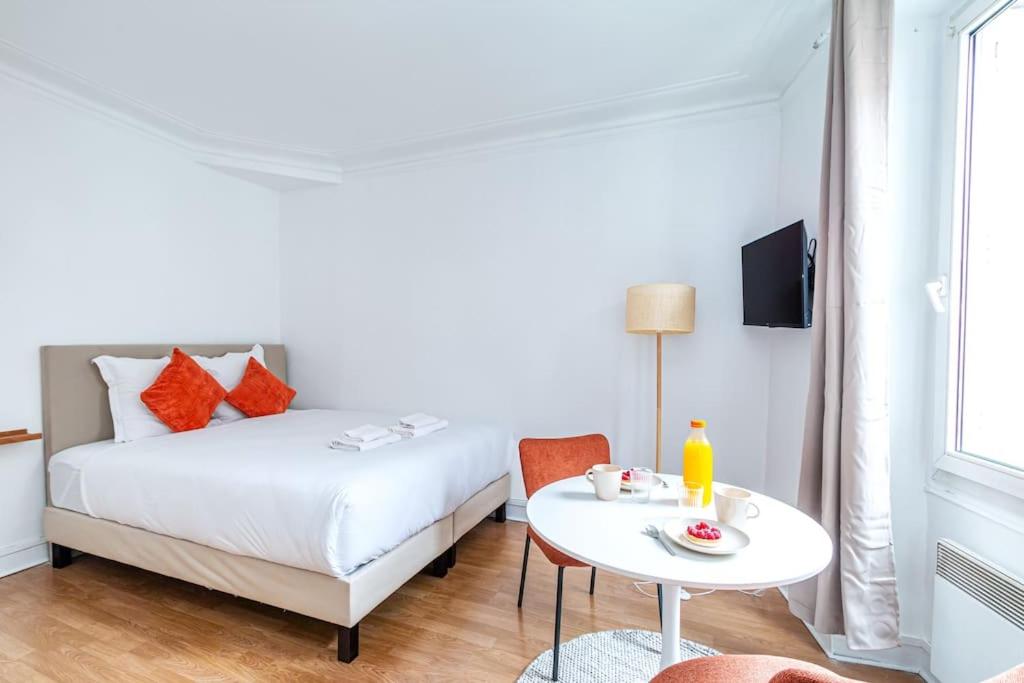 - une chambre avec un lit blanc et une table avec une tasse de café dans l'établissement Studio Avenue Philippe Auguste, à Paris