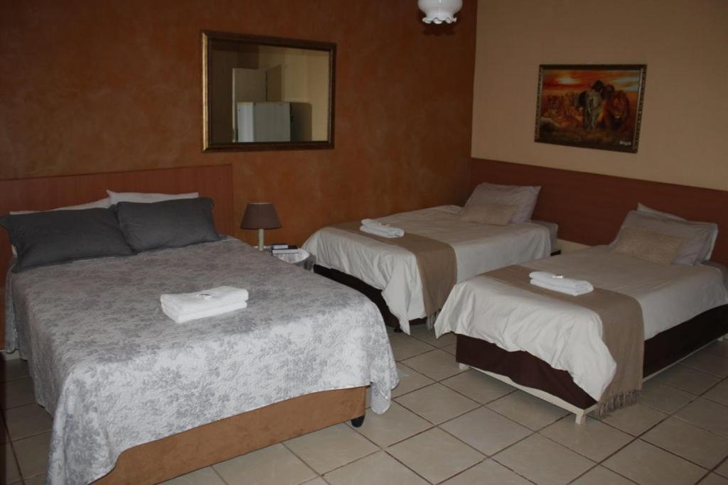 a hotel room with two beds and a mirror at Apollo Guest House in Mahikeng