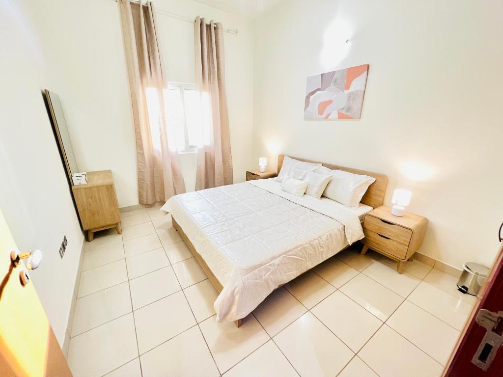 a white bedroom with a bed and a window at Cozy 1 Bedroom apartment in Dubai by Al Ghaimah Holiday Homes in Dubai
