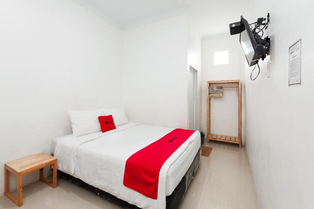 1 dormitorio con cama blanca y manta roja en RedDoorz Syariah near RSUD Zainoel Abidin Banda Aceh en Banda Aceh