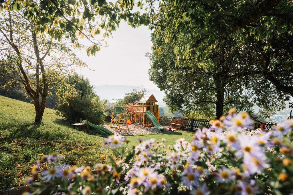 a playground in a park with flowers in the foreground at Hörandlhof in Aigen im Ennstal